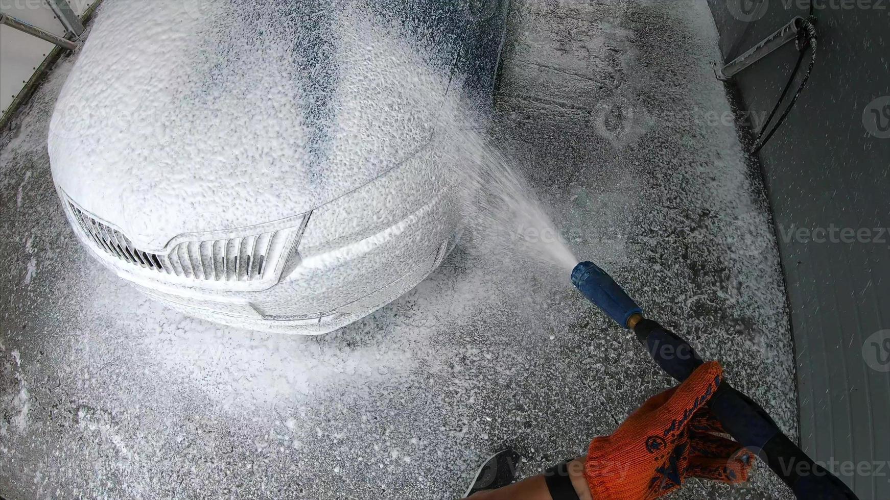 Young man covered soap suds on his car photo