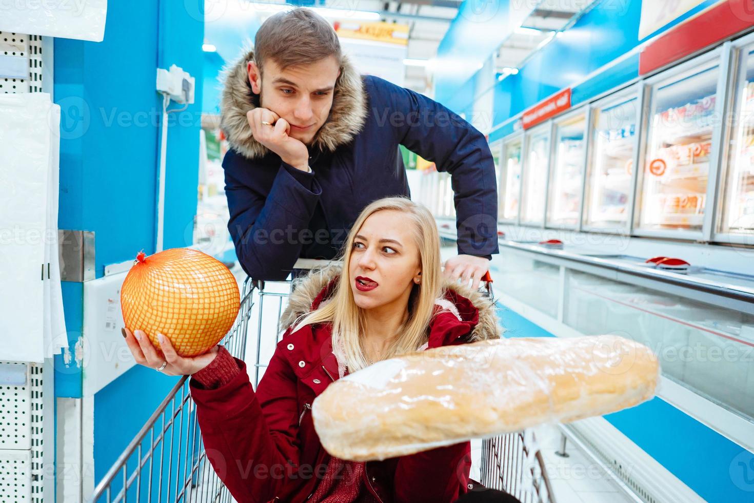 Young handsome guy rides a girl in a supermarket in a trolley photo