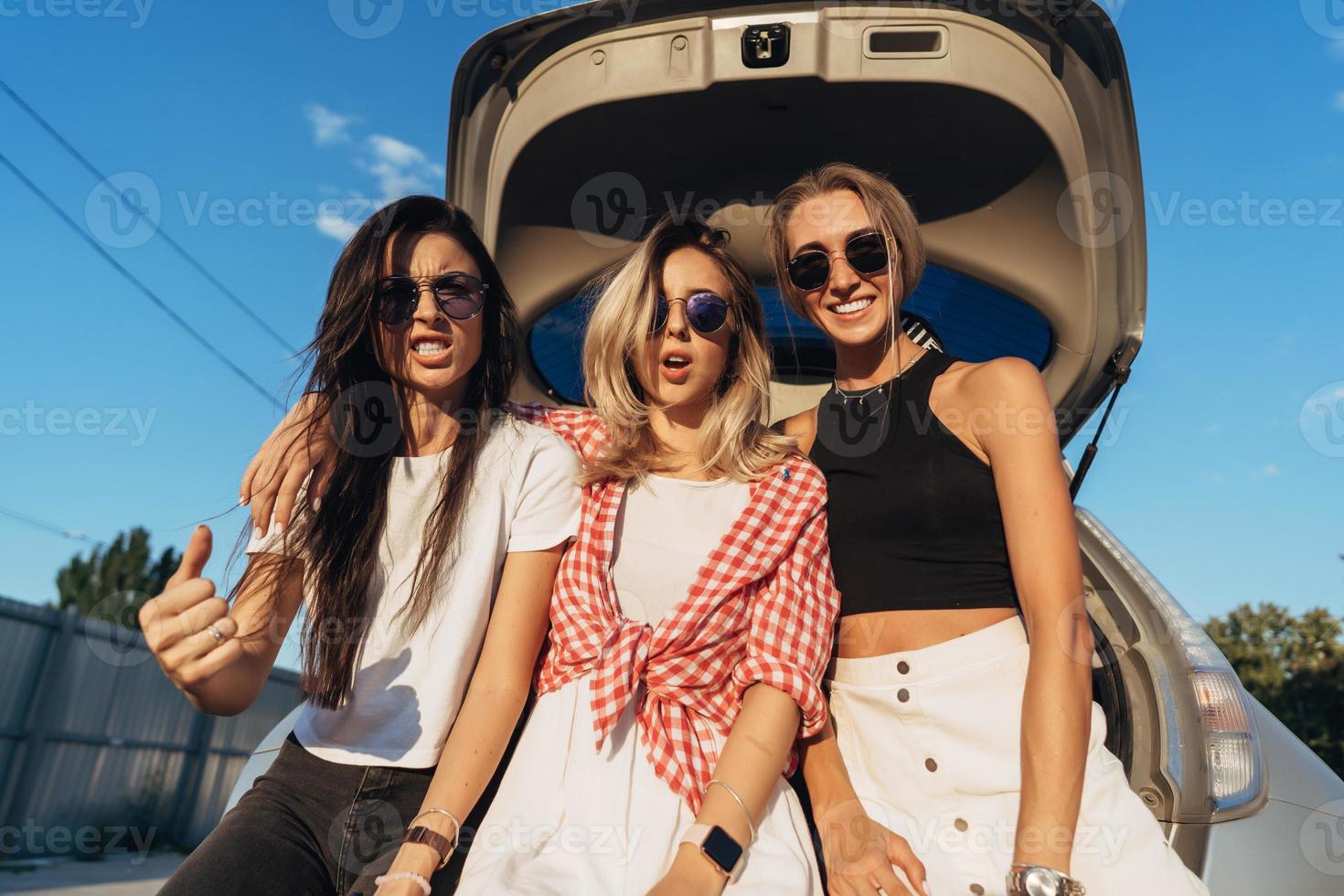 Three young woman posing for the camera the car park. photo