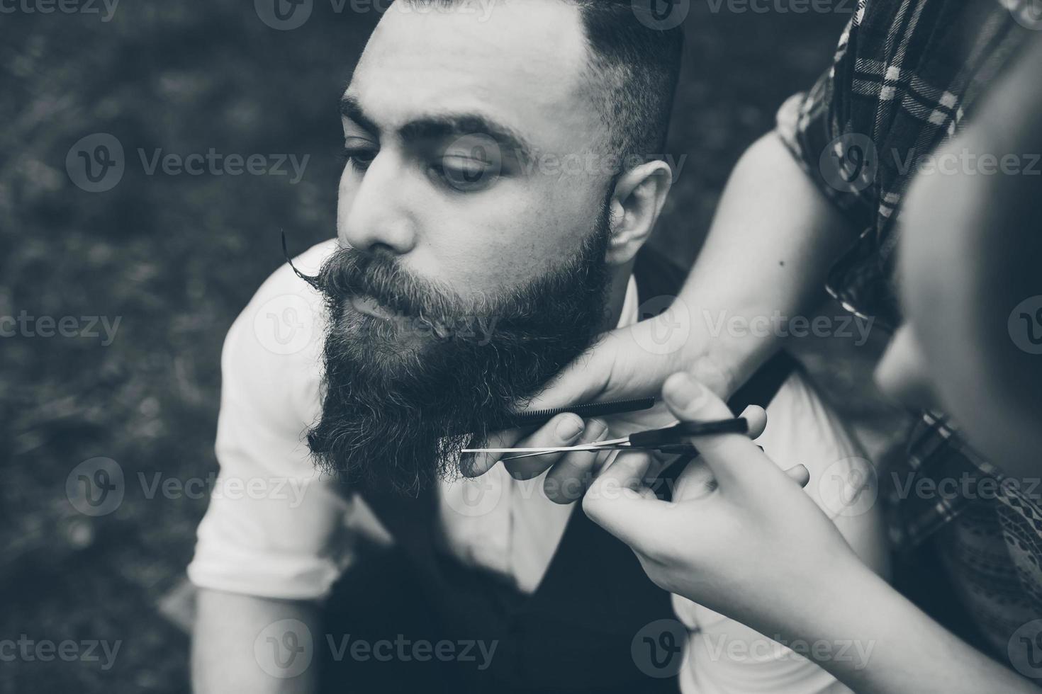 barbero afeita a un hombre barbudo foto