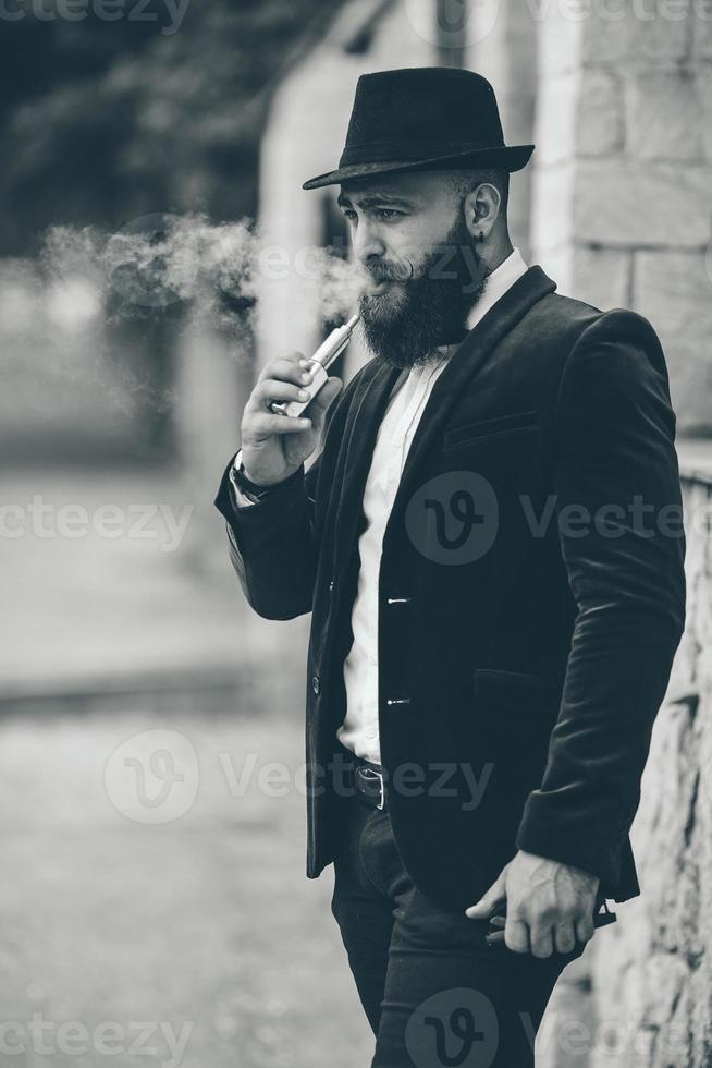 A rich man with a beard smokes electronic cigarette photo