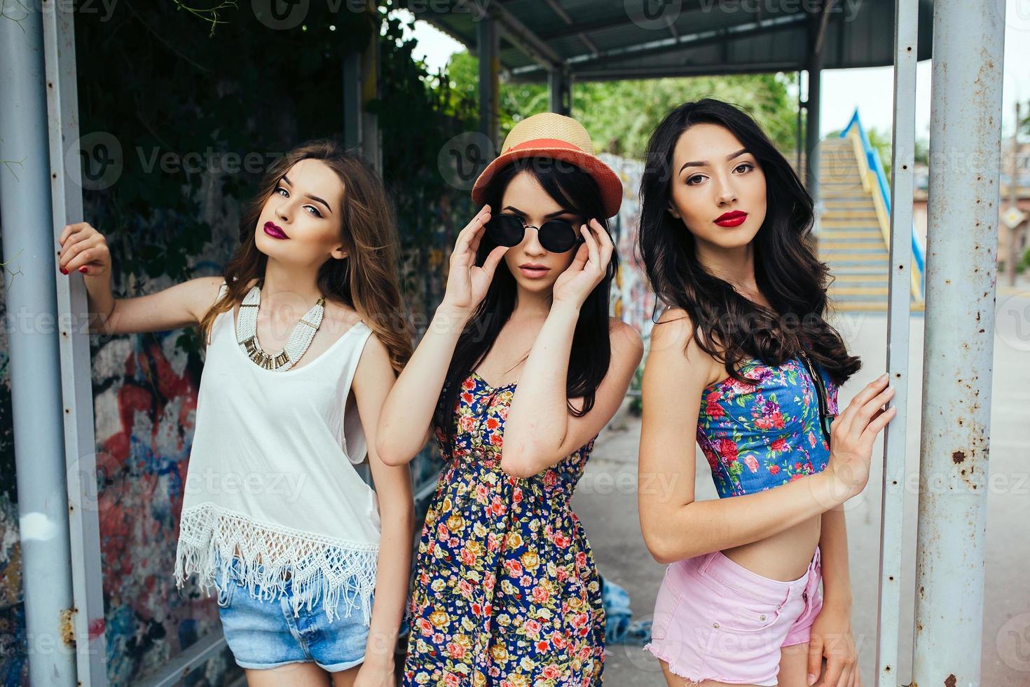 Three beautiful young girls at the bus stop photo