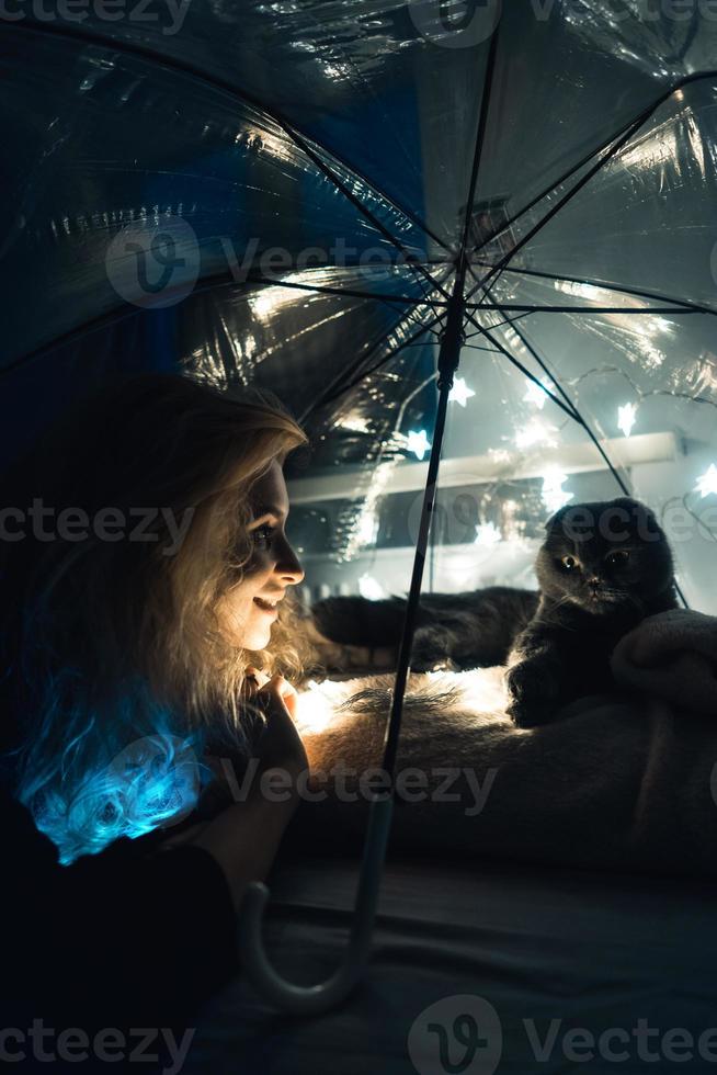 A cat and woman under an umbrella with garlands photo