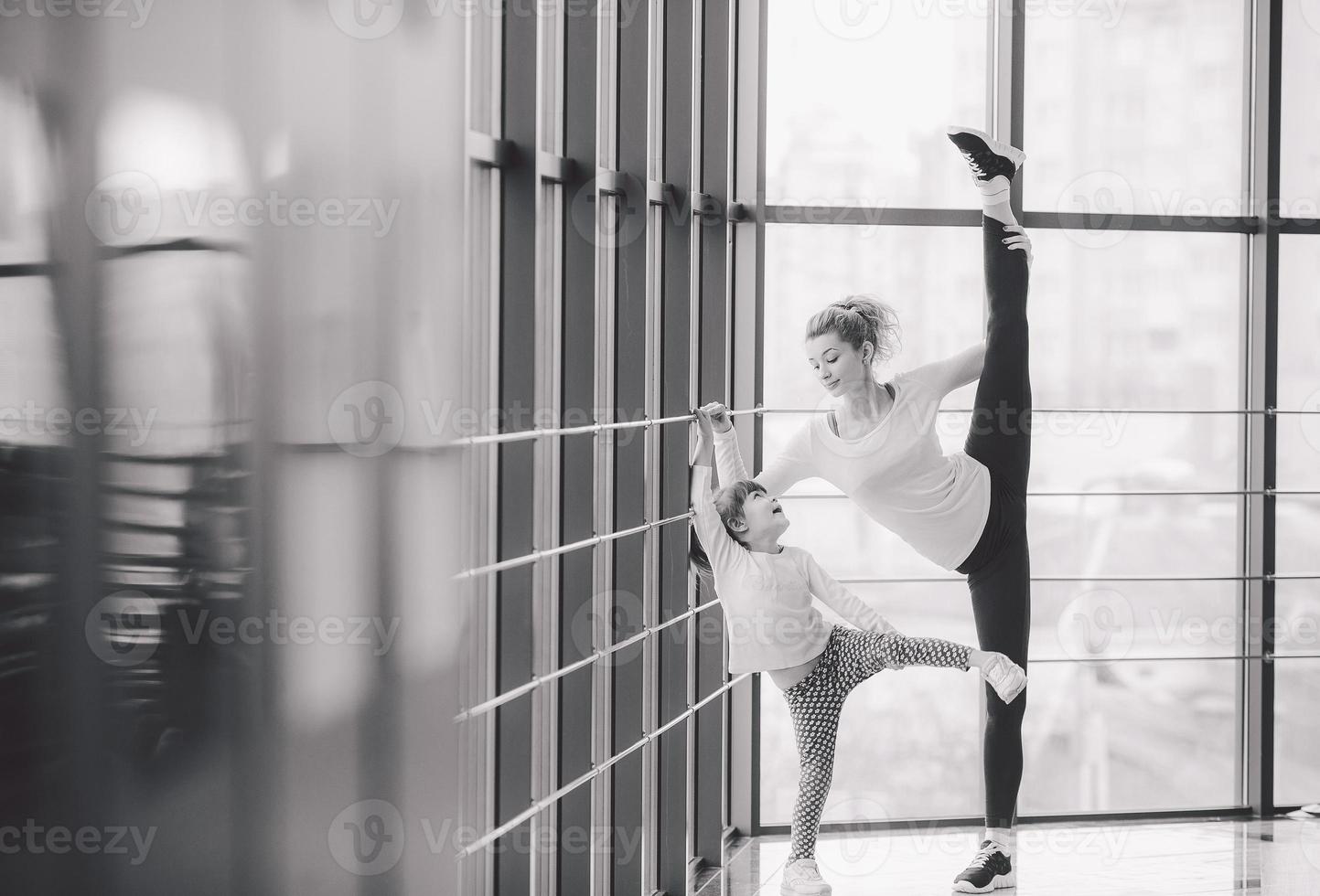 Mother learning daughter to make a high leg strech photo