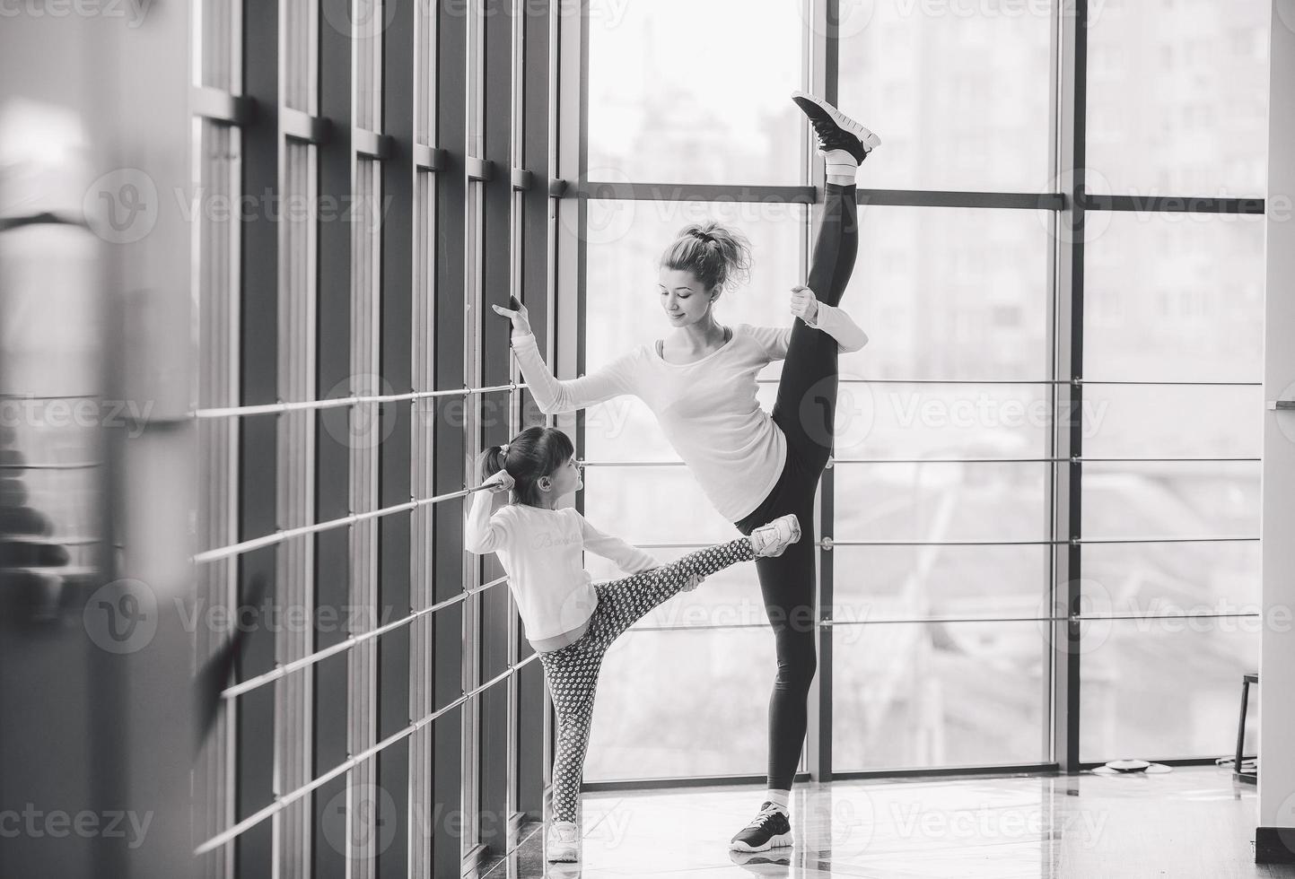 madre aprendiendo a hija a hacer un estiramiento alto de piernas foto