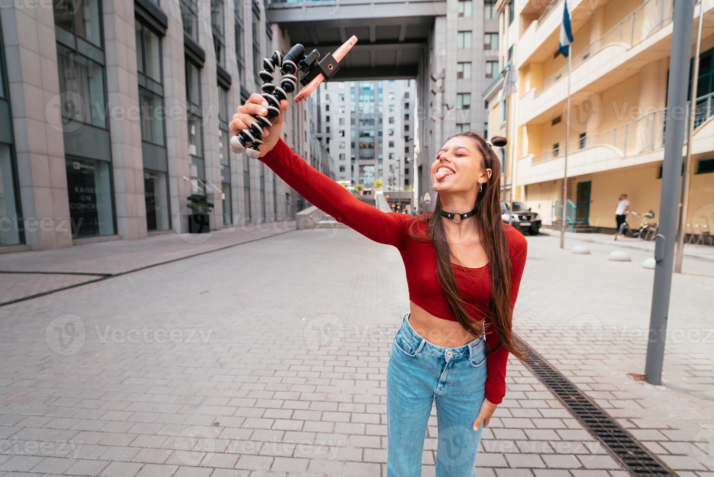 Young female blogger with smartphone streaming on the street. photo