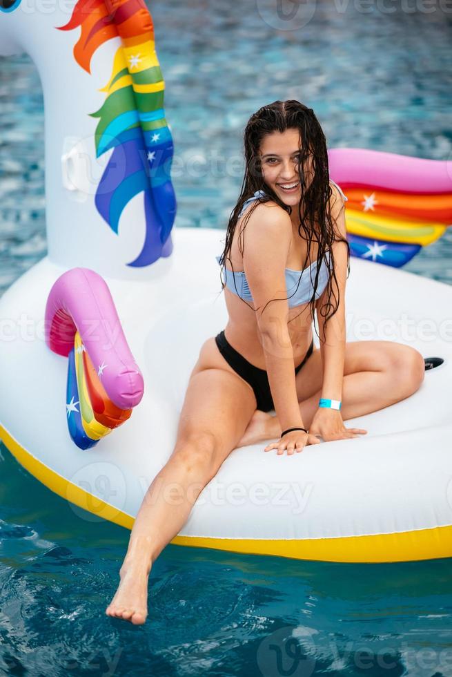 Woman on inflatable unicorn toy mattress float in pool. photo
