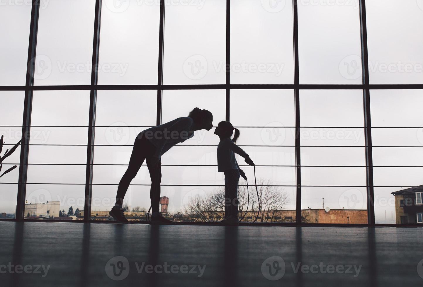 Silhouette of mother and daughter in the gym.Kiss photo