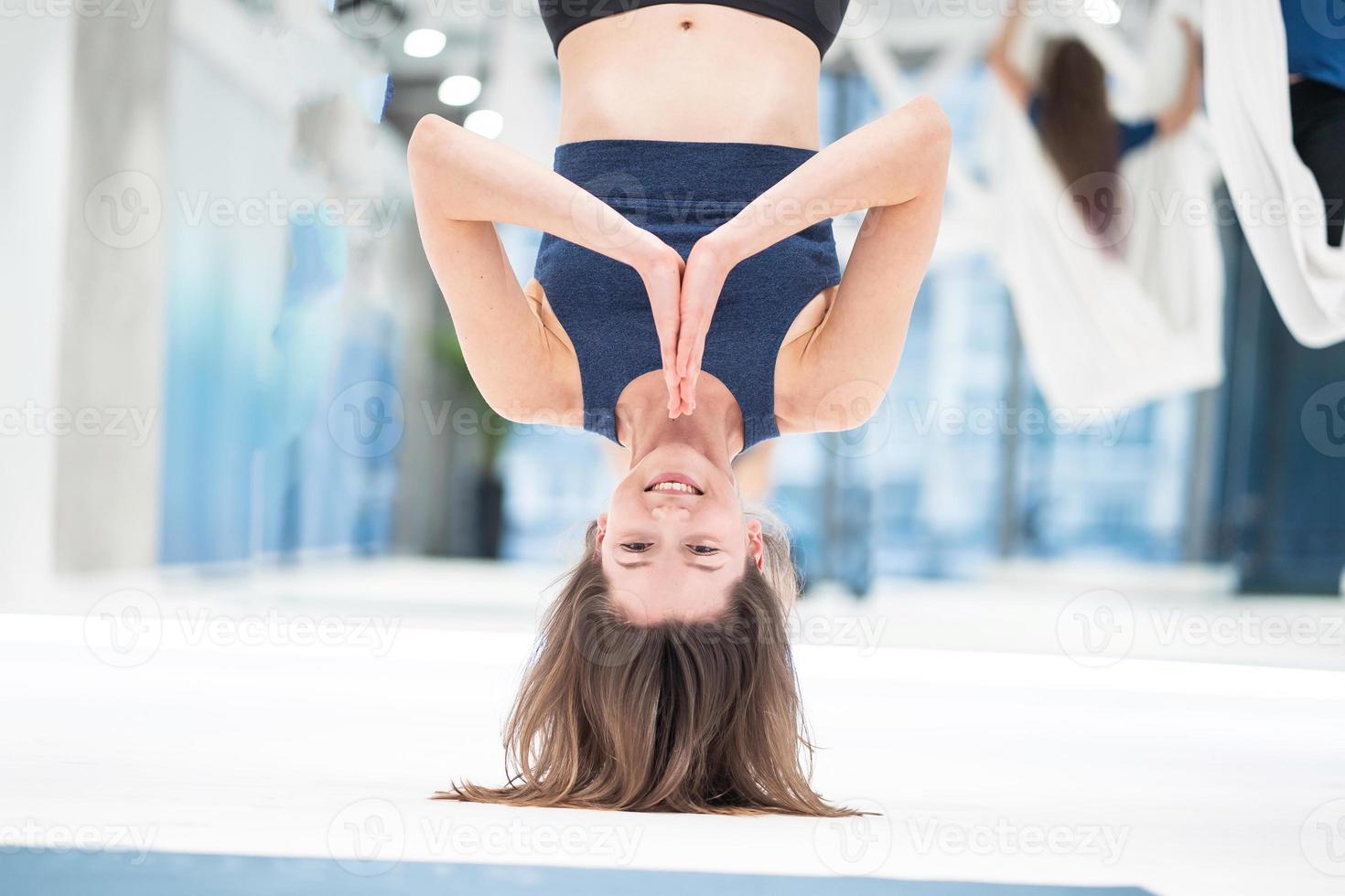 Woman hanging upside down in a hammock. Fly yoga class. photo