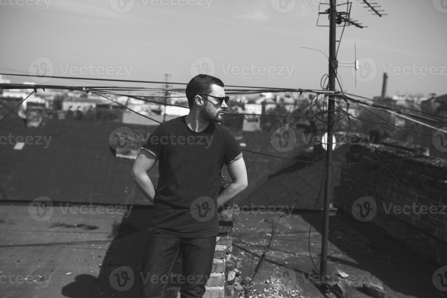 El hombre de las botas auténticas y el orillo de jeans en el techo del edificio en el casco antiguo foto