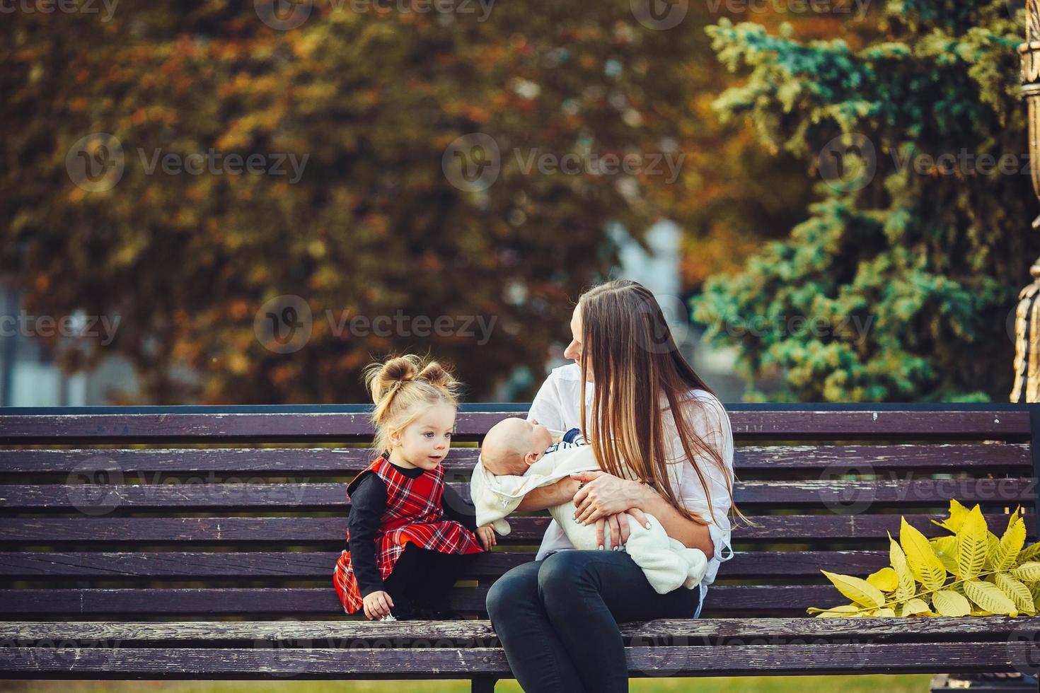 mother and two daughters rest on a bench photo