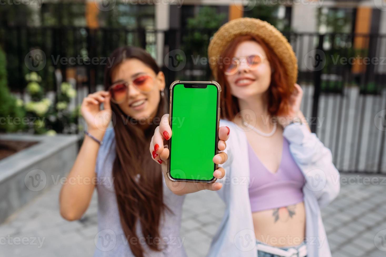 Girlfriends shows their phone to the camera photo