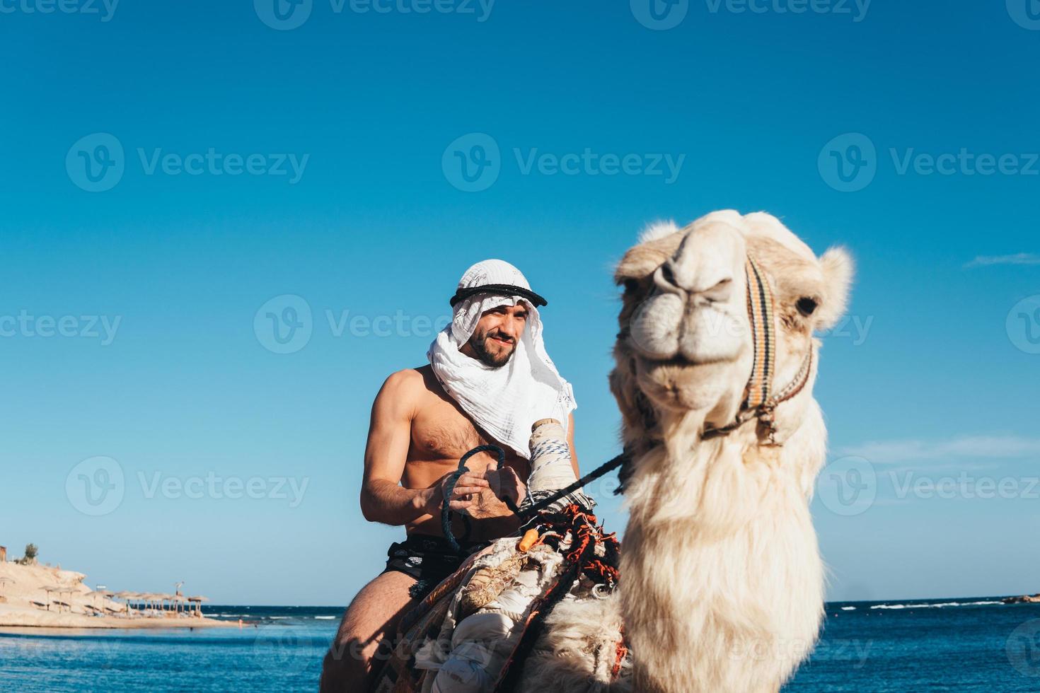 Guy rides on a camel on the beach photo