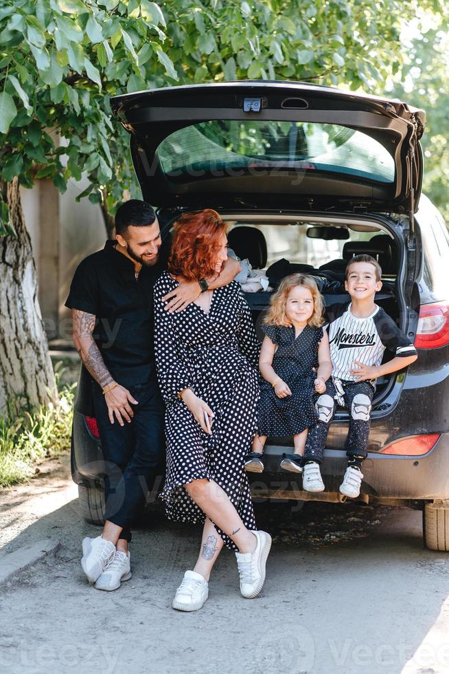 Happy family posing on camera near the car photo