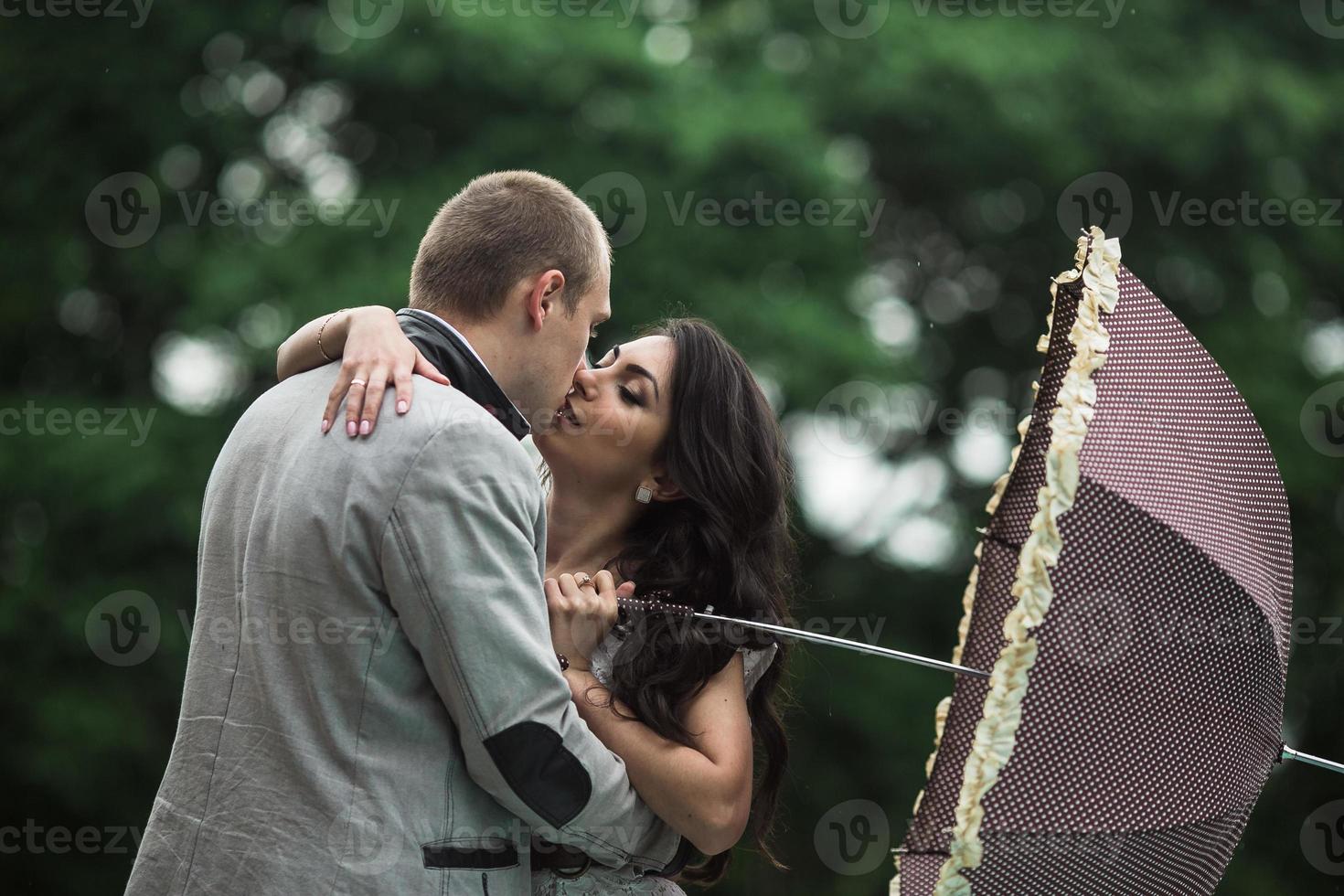 Young and beautiful European couple hiding from the rain under an umbrella photo