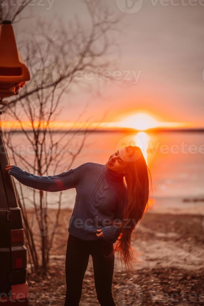 mujer disfrutando del tiempo relajándose junto al hermoso lago al amanecer. foto