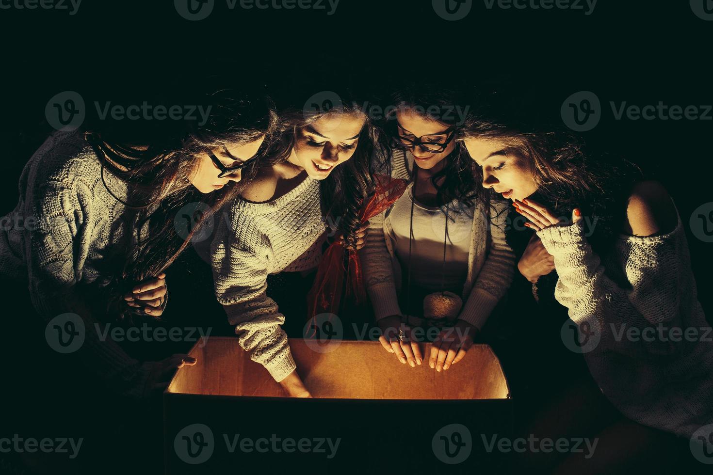 Sisters opens a box with a Christmas present and fascinated looks inside photo