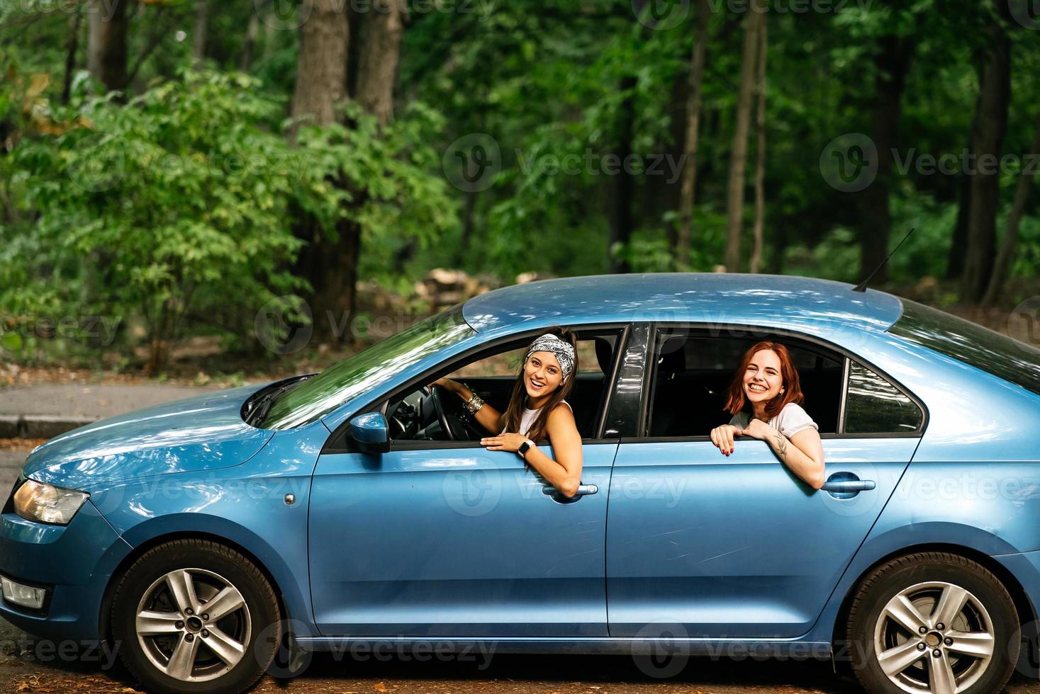 Two girlfriends fool around and laughing together in a car photo