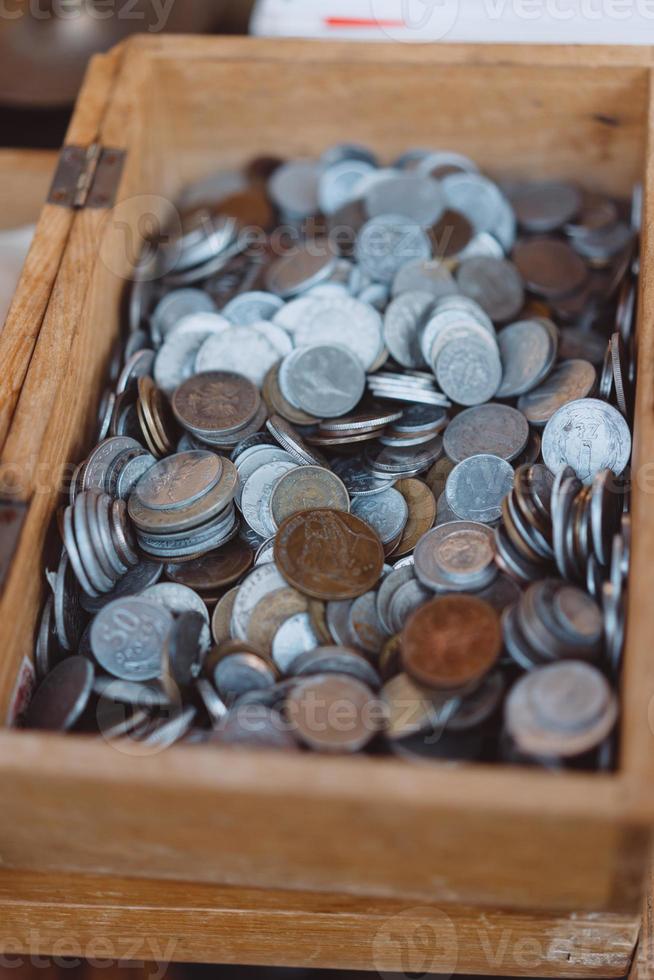 Old coins of different denominations are in a small wooden box photo