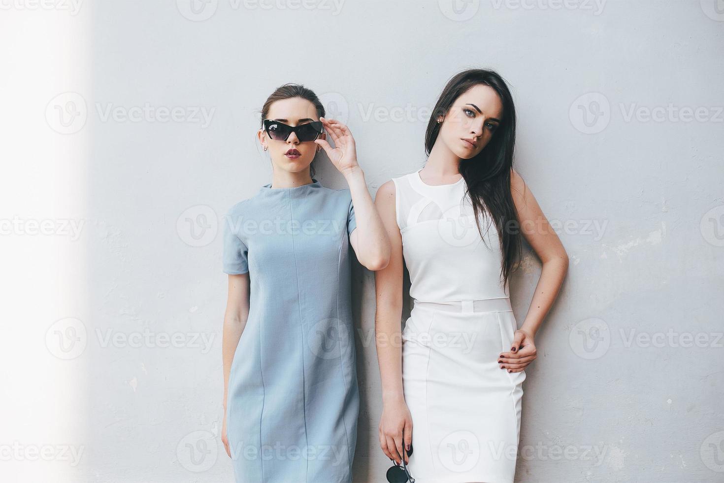 Two beautiful friends pose on white background photo