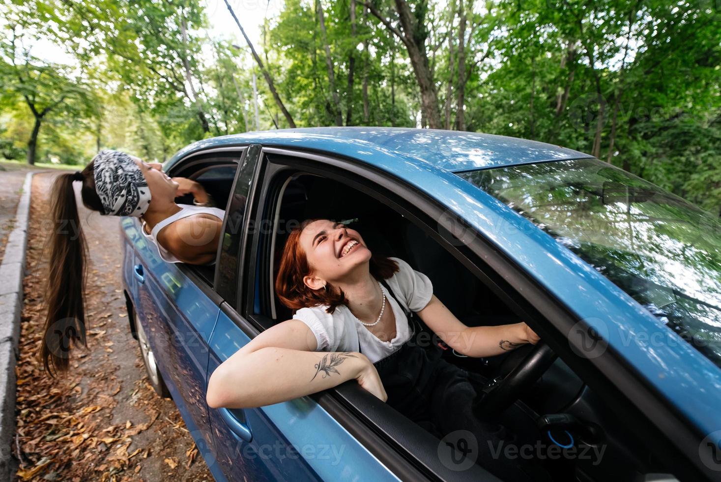 Two girlfriends fool around and laughing together in a car photo