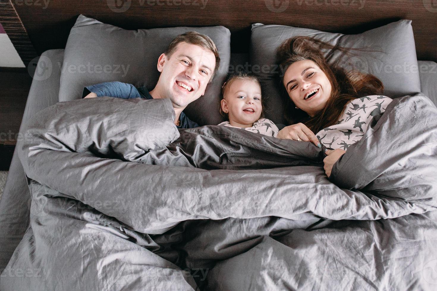 happy child with parents in bed at home 11367604 Stock Photo at Vecteezy