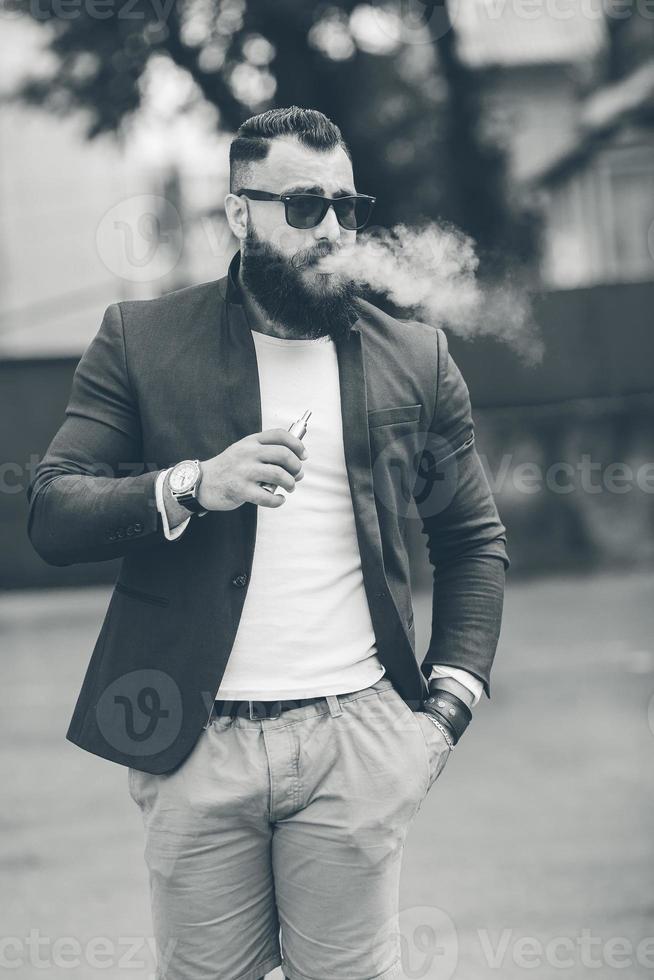 man with a beard smokes electronic cigarette photo