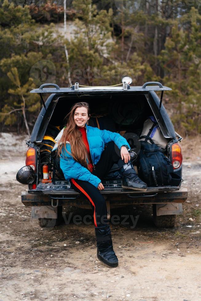 Young woman enjoying nature while sitting in the car trunk photo