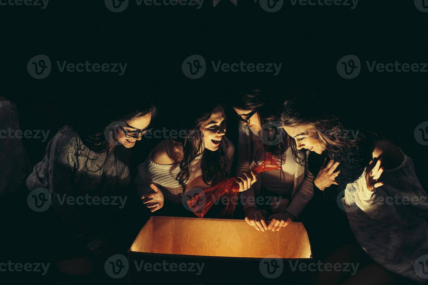 Sisters opens a box with a Christmas present and fascinated looks inside photo