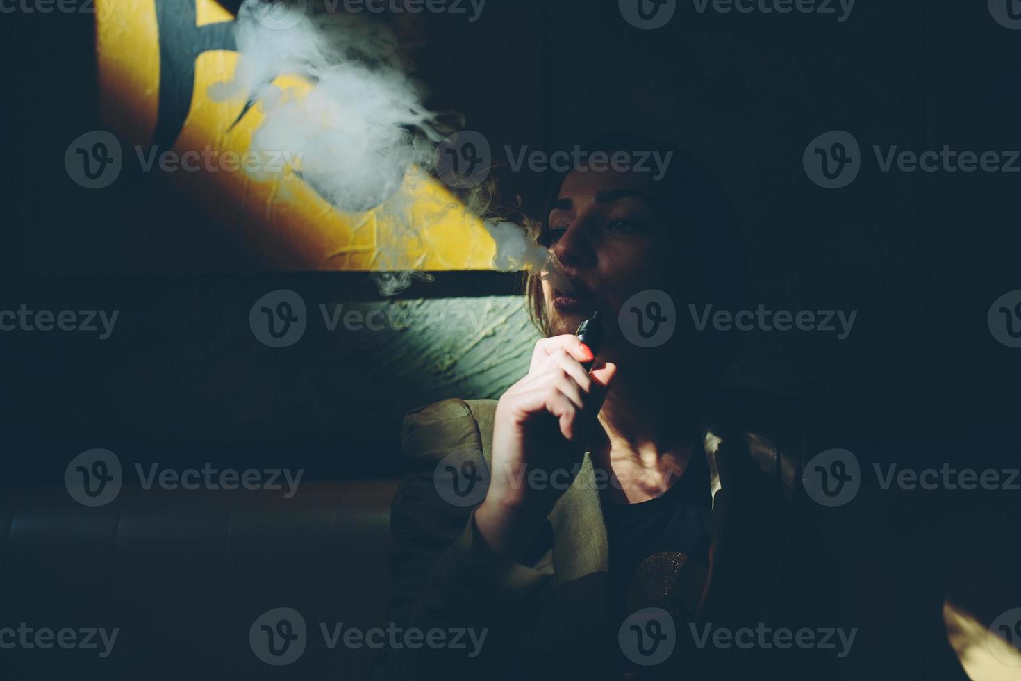chica se sienta y fuma cigarrillo electrónico foto