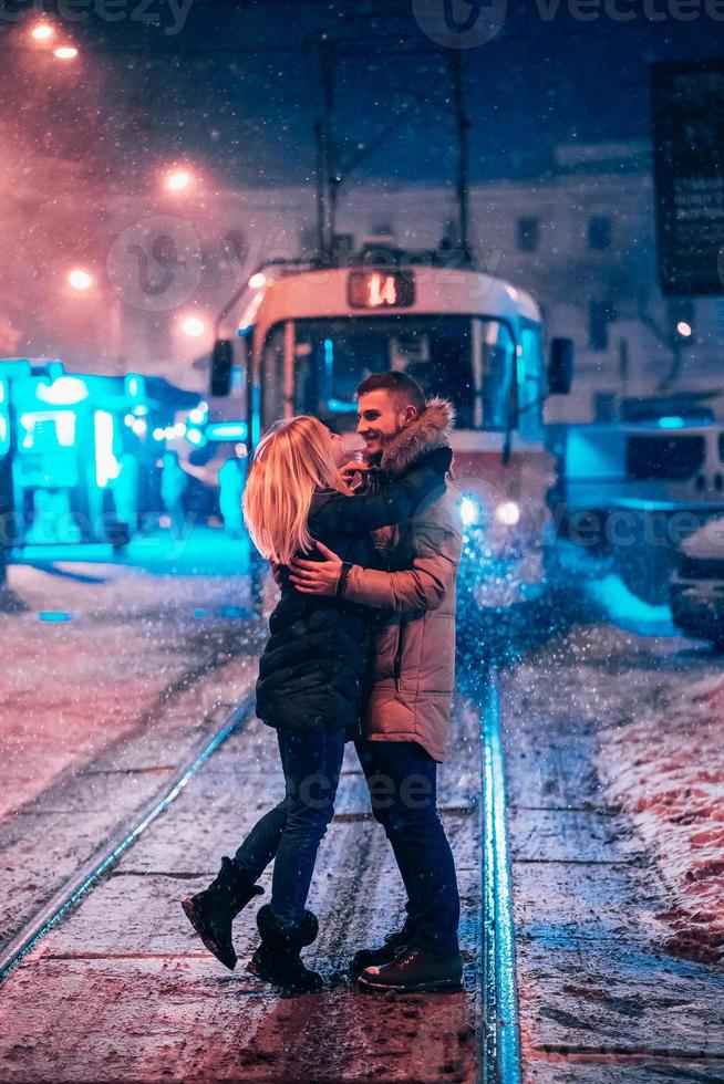 pareja de adultos jóvenes en la línea de tranvía cubierta de nieve foto