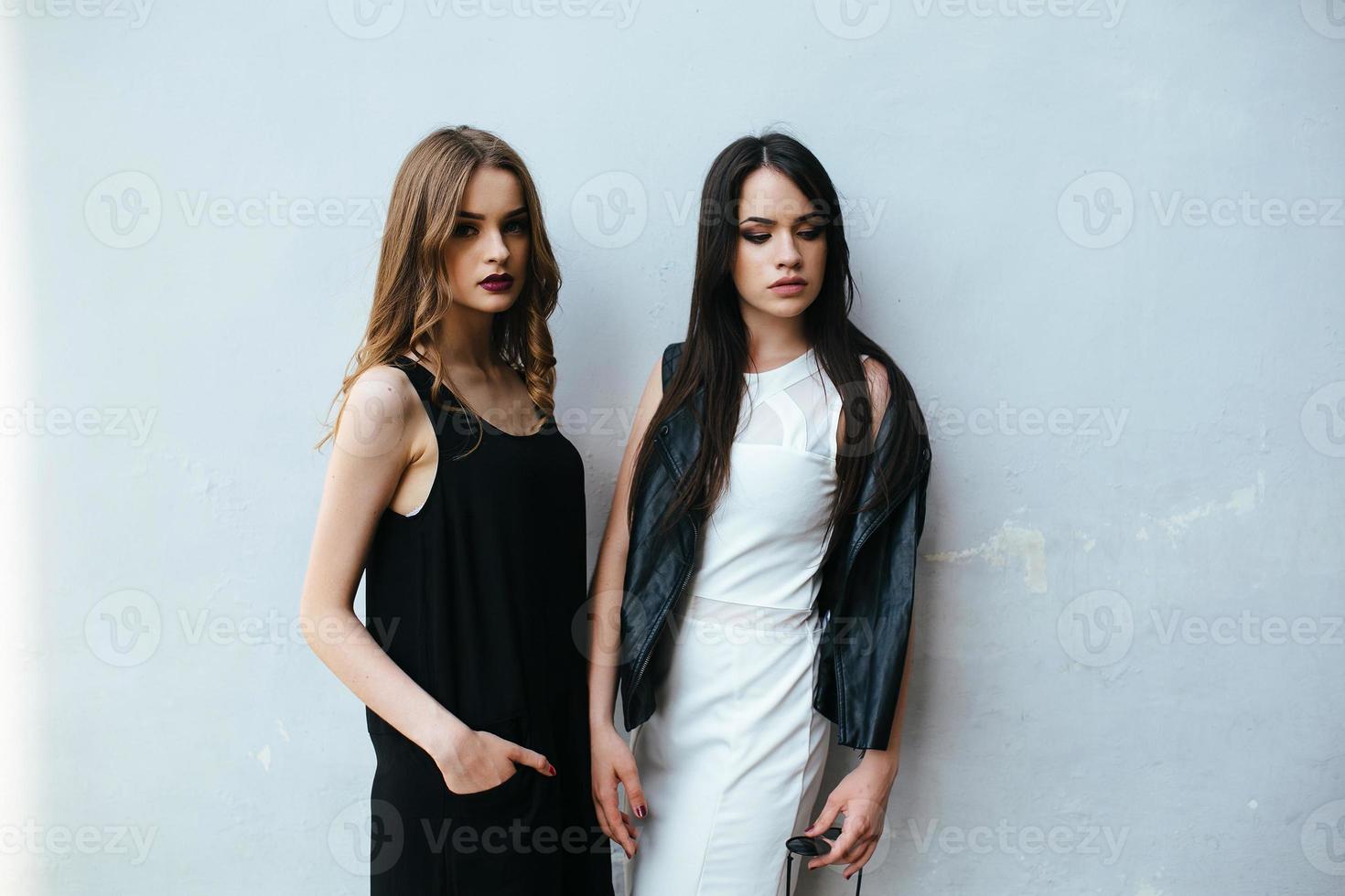 Two beautiful friends pose on white background photo