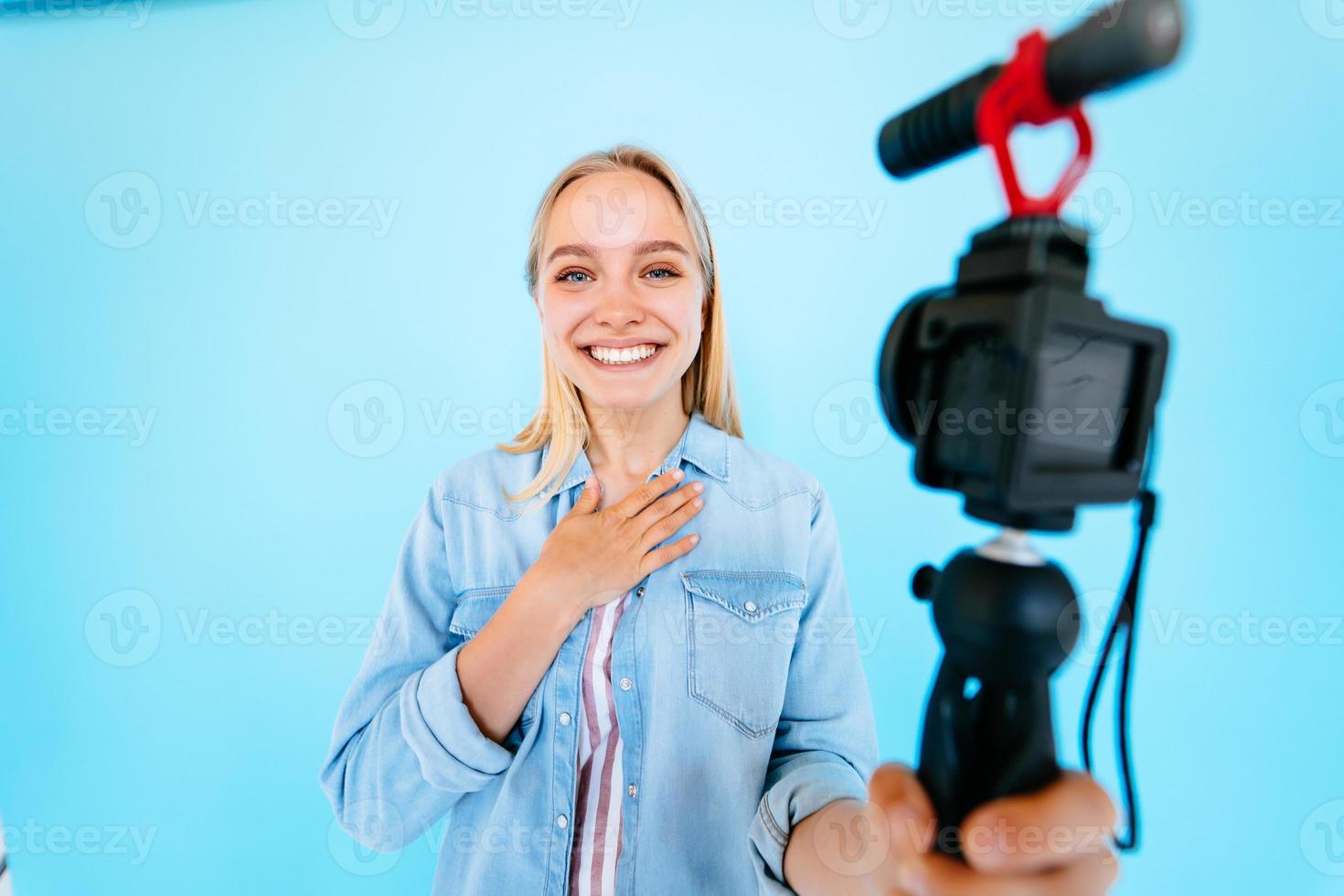 Beautiful girl blogger relieves itself at camera isolated blue background photo