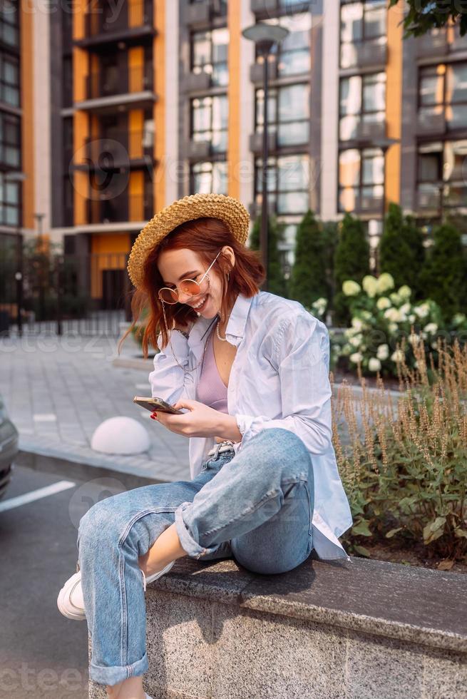Young lady sitting stairs typing device outside urban city street photo