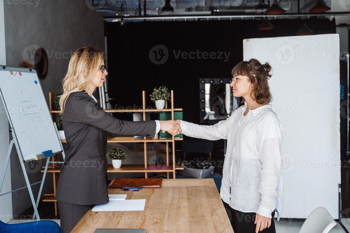 Two Businesswomen Shaking Hands In Office photo