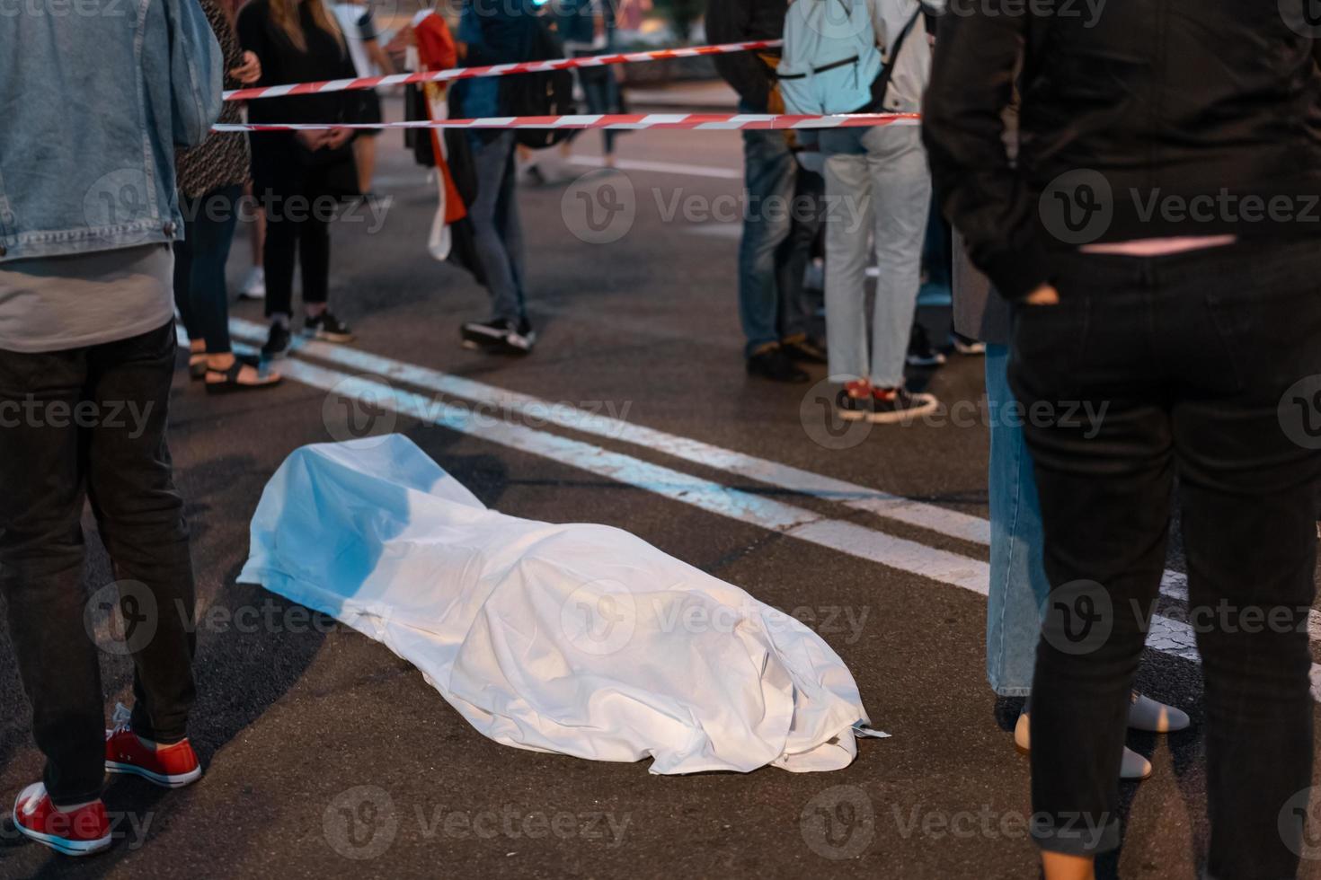 Human body covered by a sheet lying on the street. photo