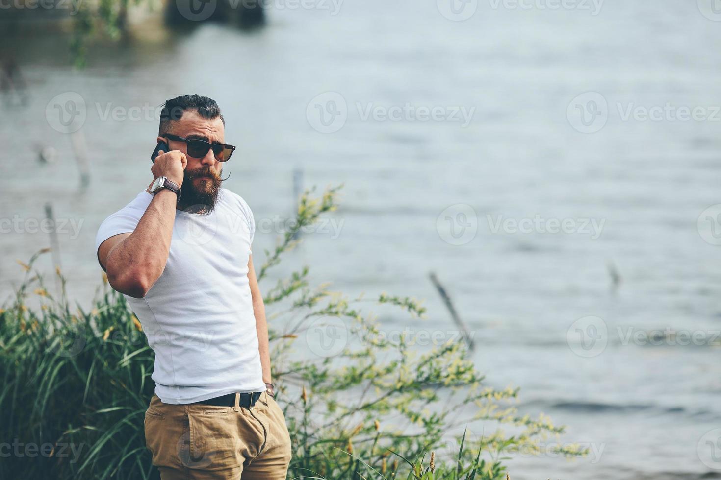American Bearded Man using phone near the river photo
