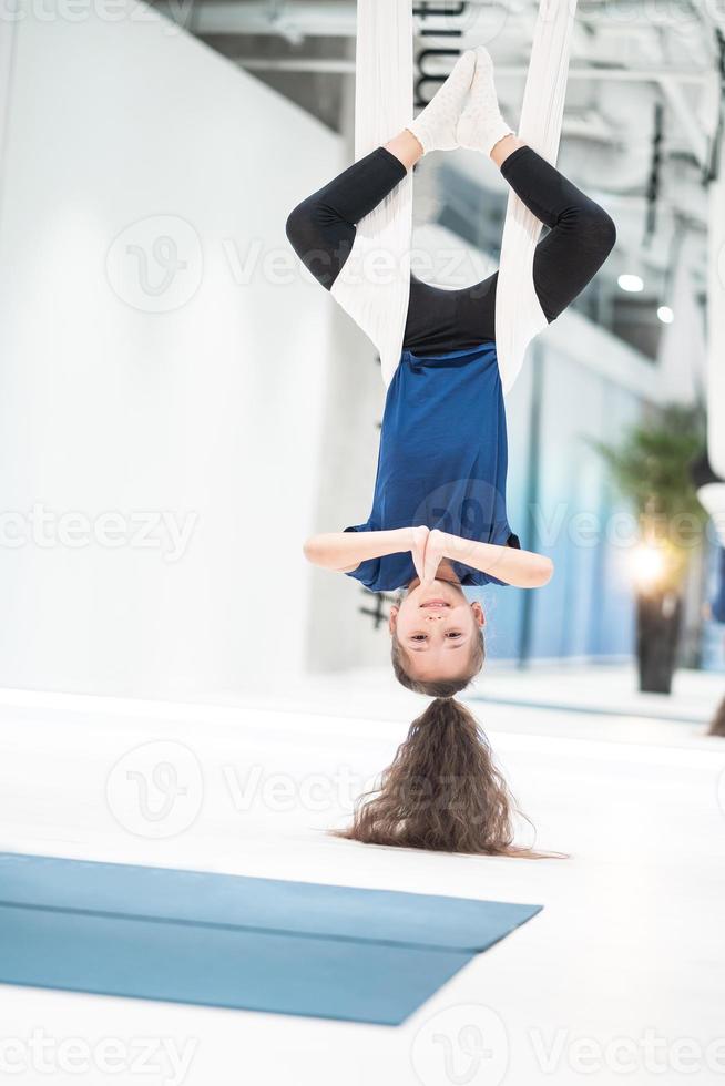 portrait of a beautiful young girl engaged in fly yoga on canvases. photo