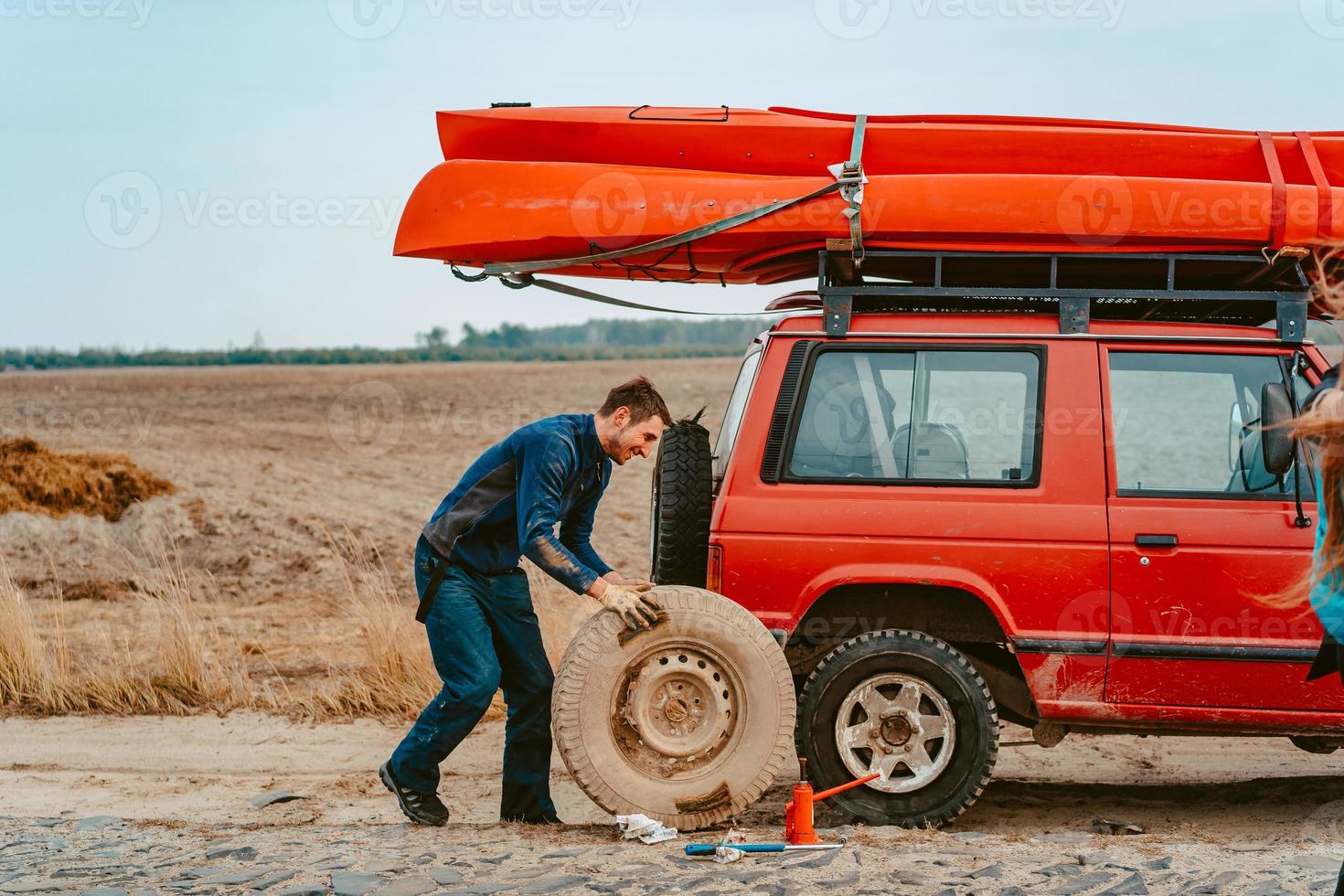 Man rolls a new replacement wheel to 4x4 off road truck photo