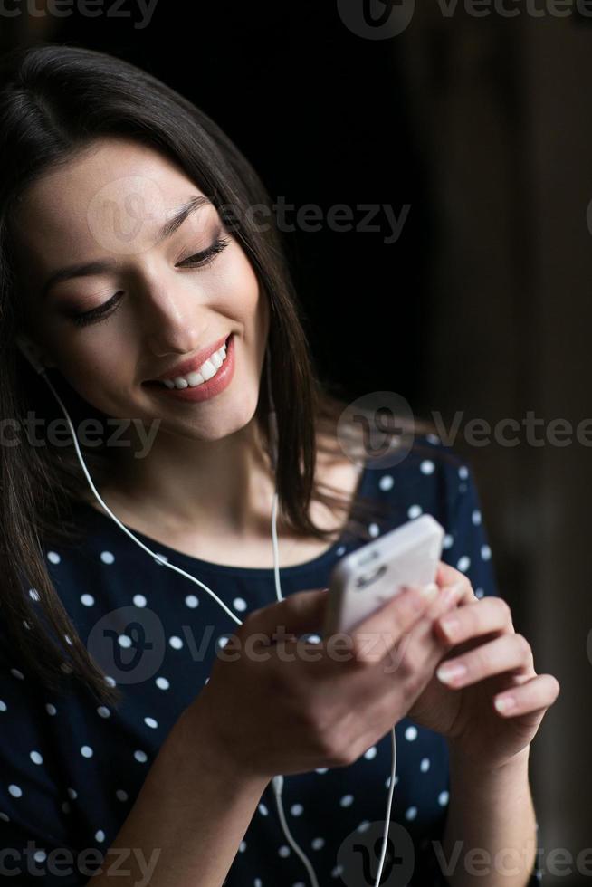 hermosa chica escuchando música en el teléfono con auriculares foto