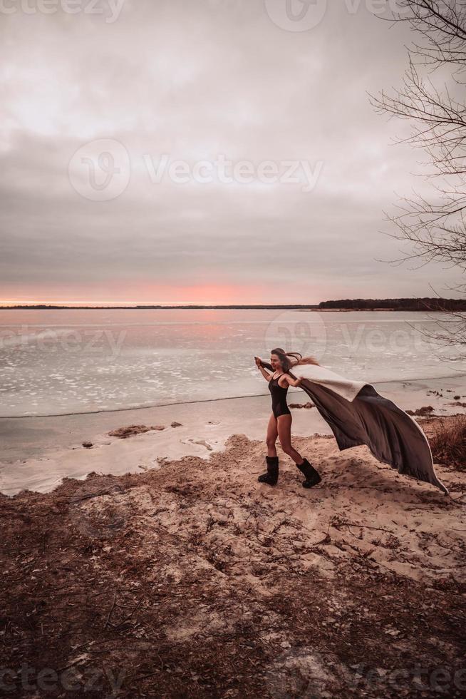 Beautiful young girl in a swimsuit on the shore of a frozen lake photo