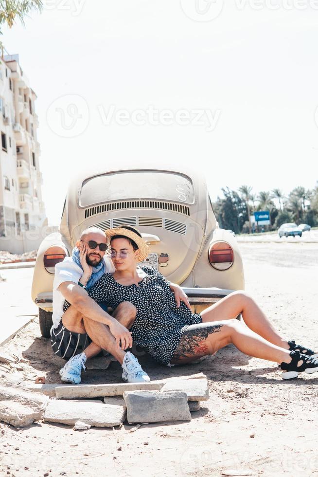 Couple sitting on the asphalt behind the car photo