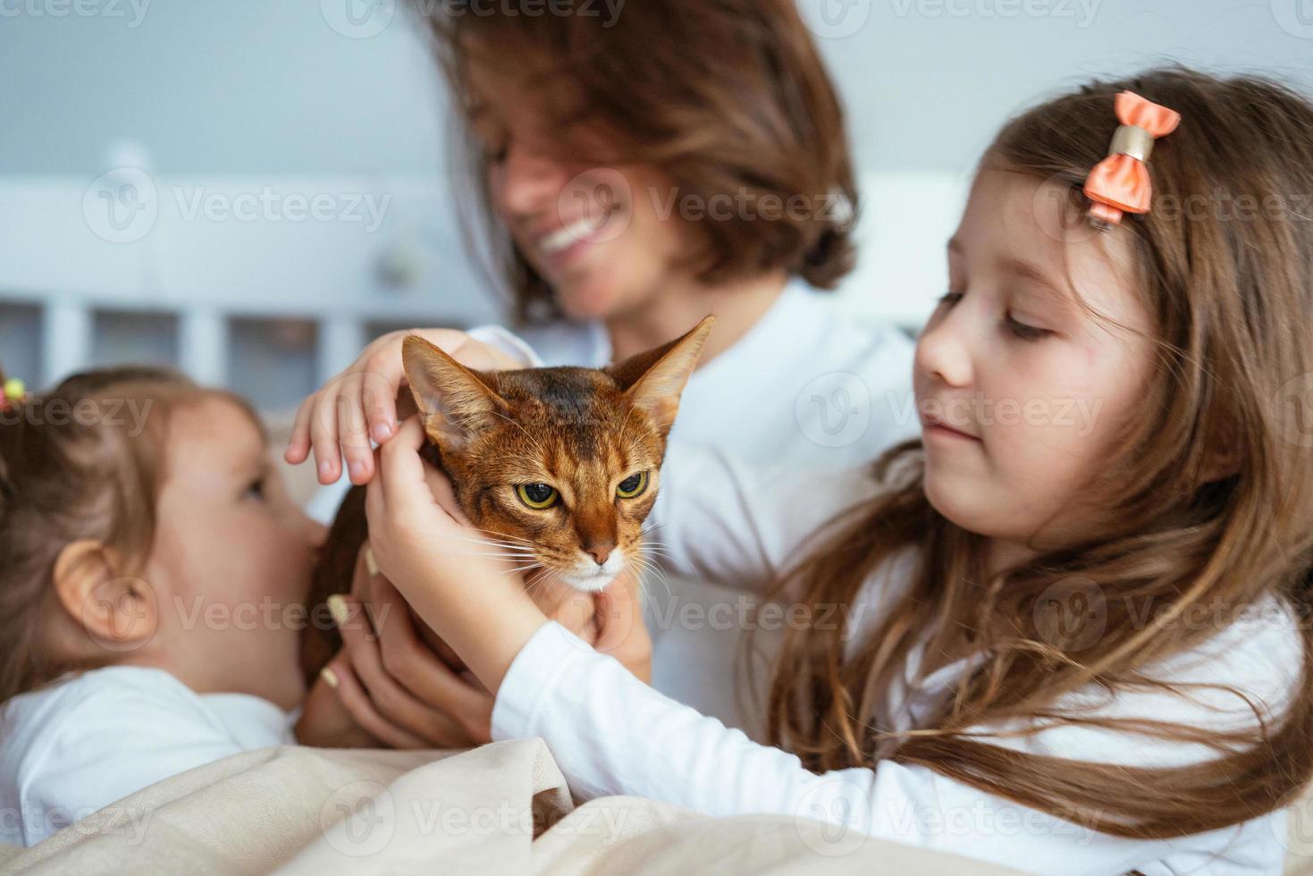 Happy mother and two daughters smiling hugs in bed photo