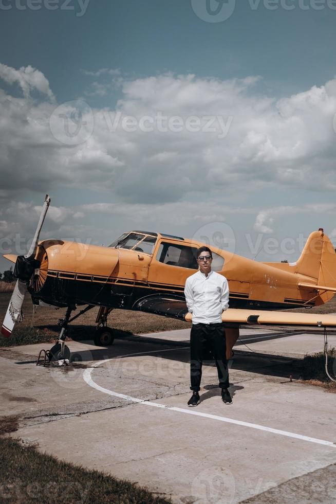 A man standing on the background of a small single engine plane. photo