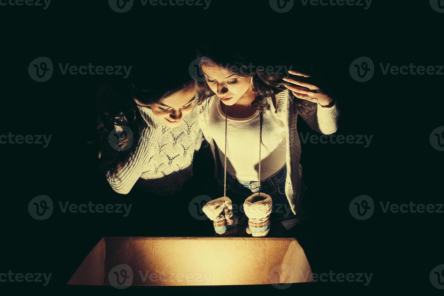 las hermanas abren una caja con un regalo de navidad y miran fascinadas dentro foto