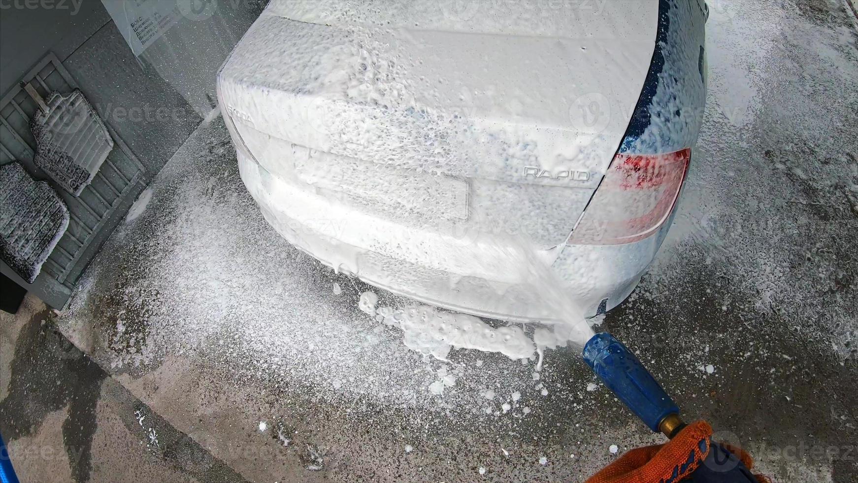 Young man covered soap suds on his car photo