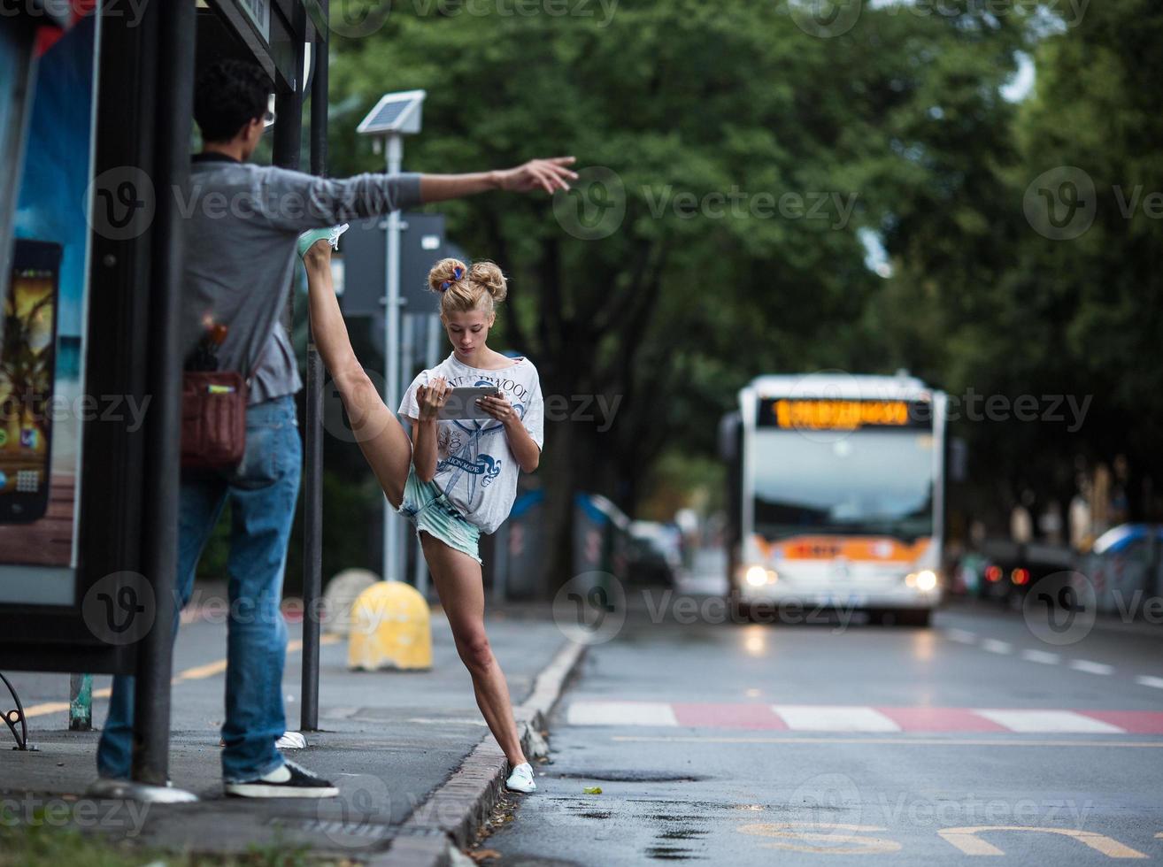 lindas chicas con tableta en una estación de autobuses con una pierna dividida foto