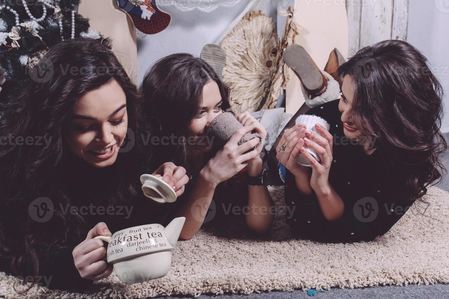 Beautiful girl eating Christmas cookies and drink tea while lying on a carpet. Decorative vintage apartment. photo