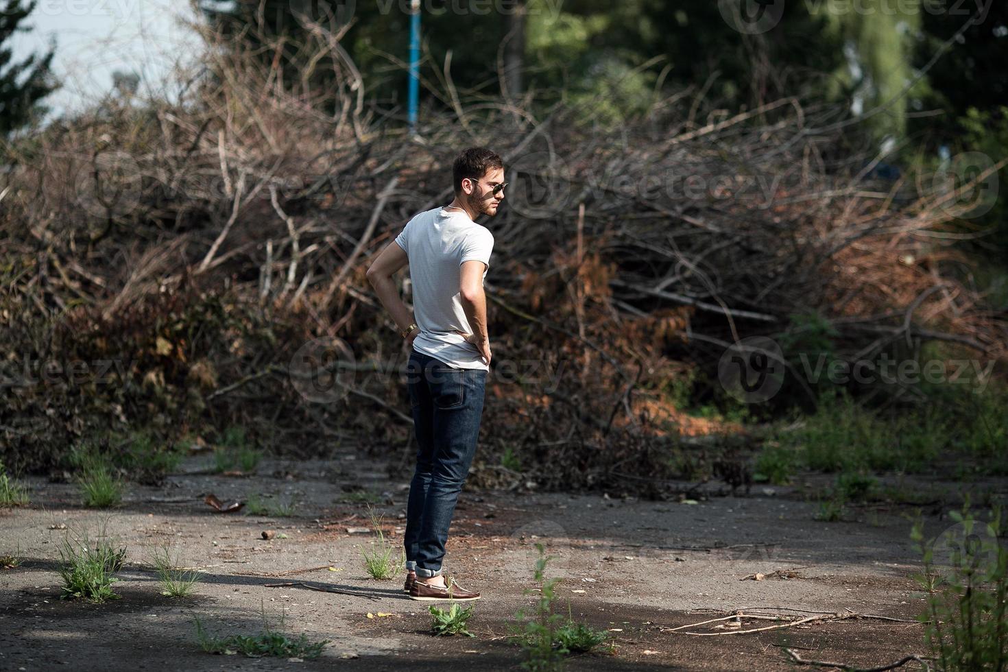 The man in the authentic boots and selvedge jeans  on a the background of branches photo