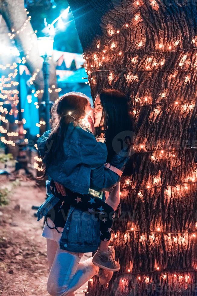 mamá besa a su hija en el parque nocturno foto